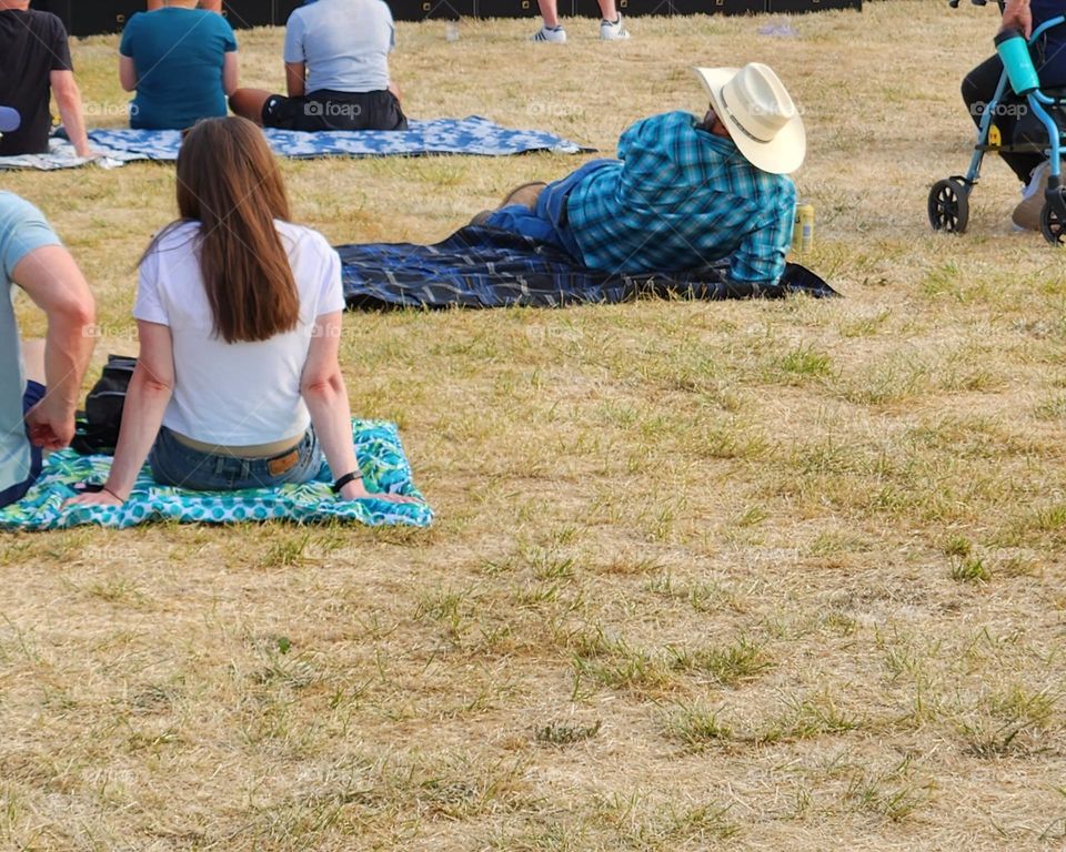 people sitting on blankets on grass lawn waiting for an outdoor concert at a county fair during Summer in Oregon