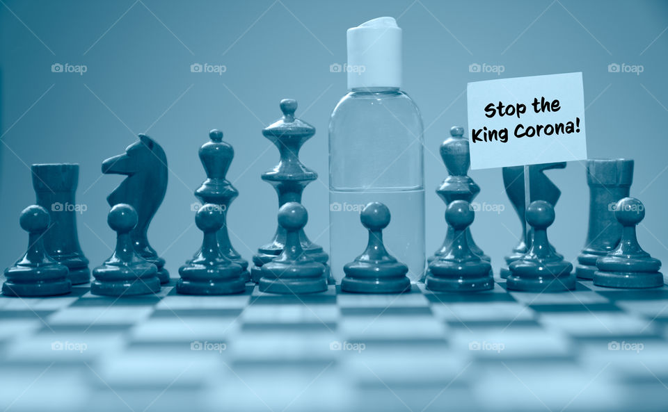 Coronavirus concept image chess pieces and hand sanitizer on chessboard illustrating global struggle against novel covid-19 outbreak.