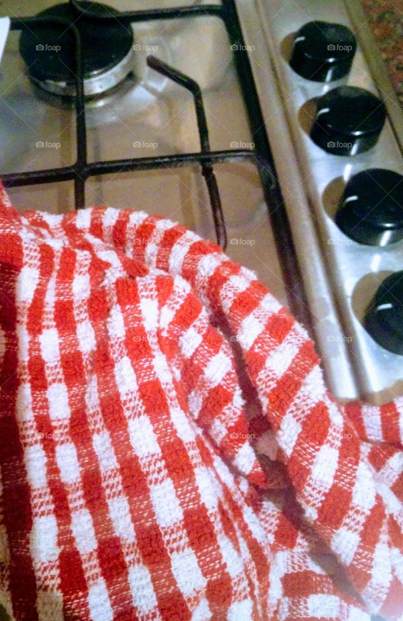 Red checkered tea towel on chrome cooking hob in kitchen.