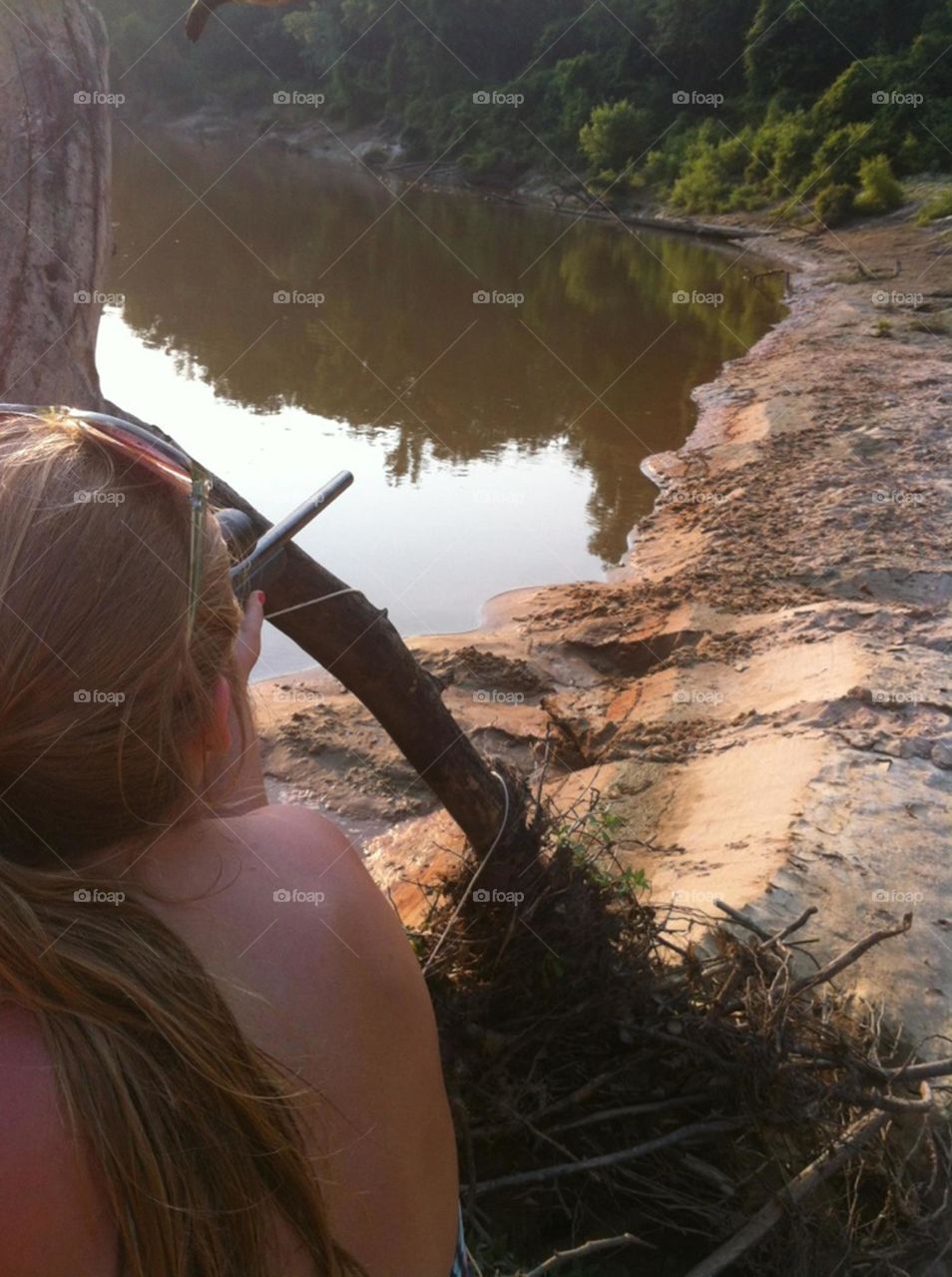 Girl shooting a gun along the riverbank 