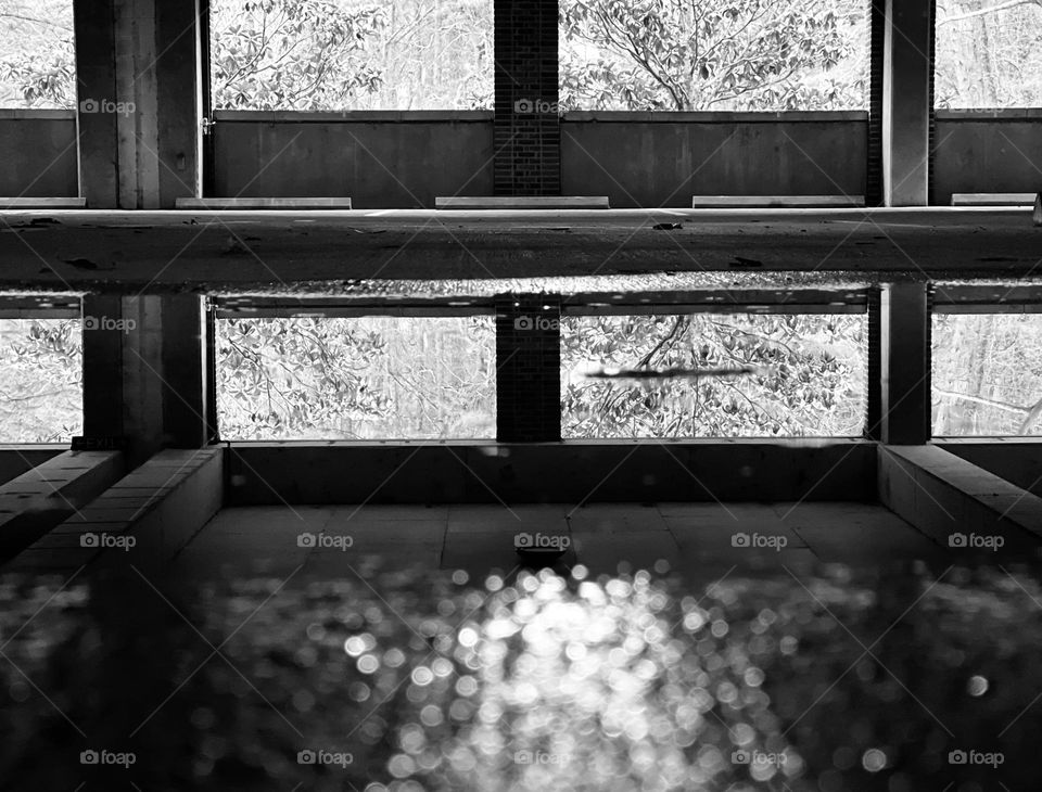 Concrete parking deck with puddle reflections in black and white. A desolate, eerie effect.