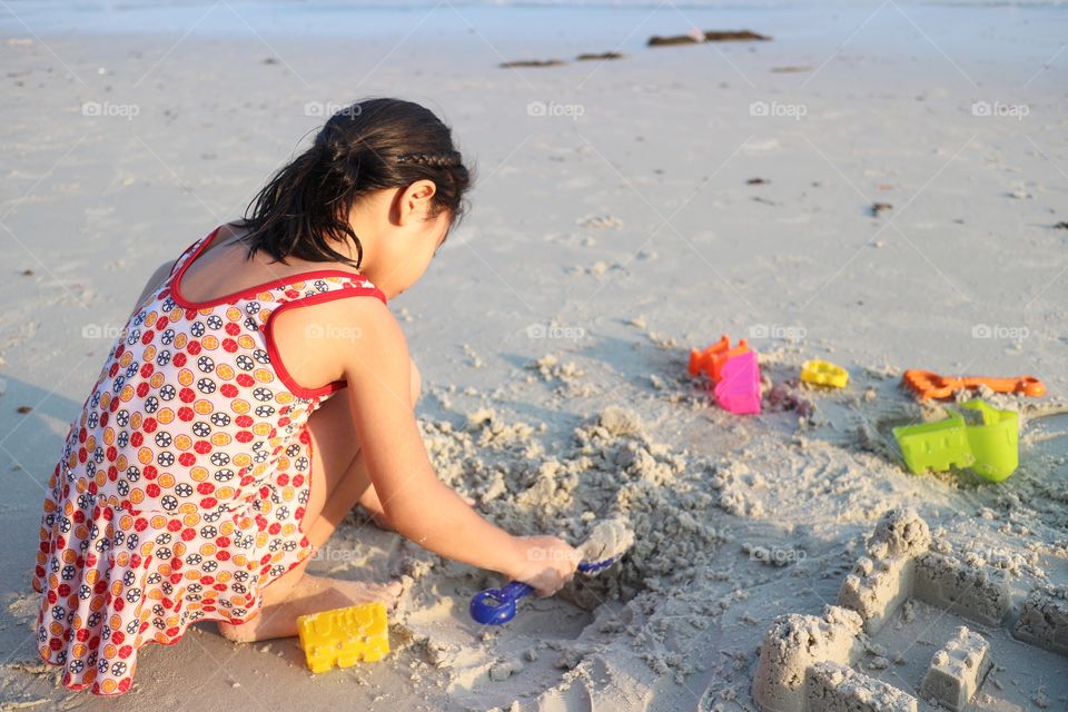 The girl playing the sand on the beach.