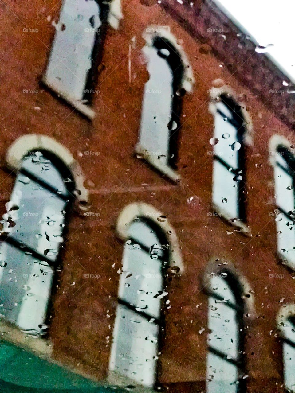 Raindrops on a sunroof looking at a building downtown
