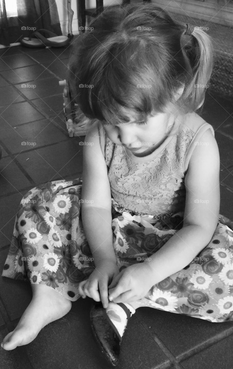 Child putting on shoes. Little girl putting on her shoes