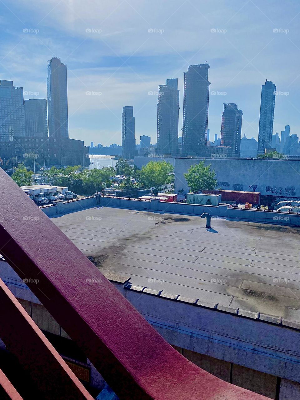 This is a view from the red metal staircase of the „Pulaski Bridge“ at „Newtown Creek“ in LIC, Queens towards the „East River“ and „Greenpoint“, Bklyn on the left, LIC high rises and in the far distance „Manhattan“. 2023. Hypnotic Productions