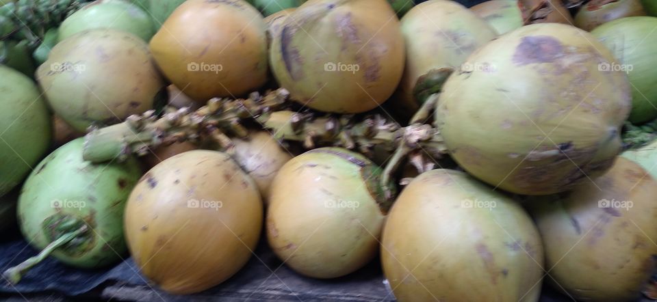 Piles of green coconuts on display.