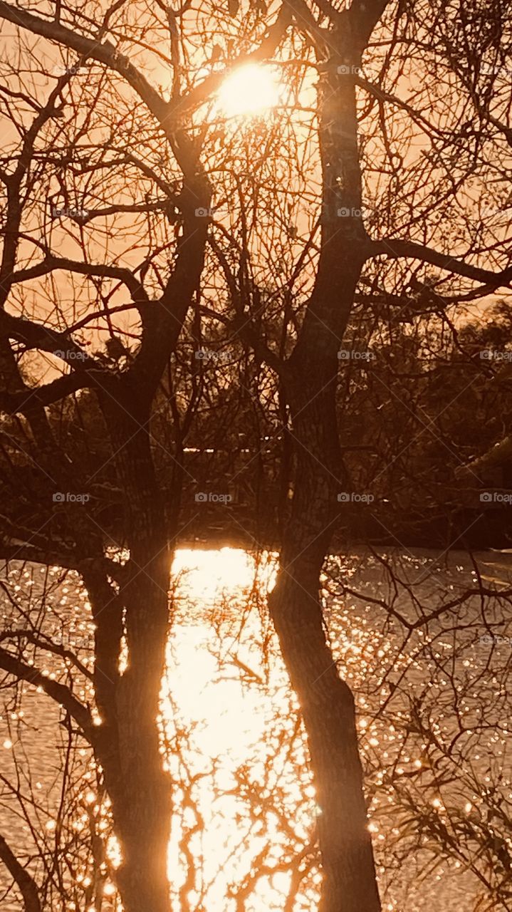 Sunset in the making. Sun’s rays bleeding down on landscape of lakebed cascading down over the lake waters. 