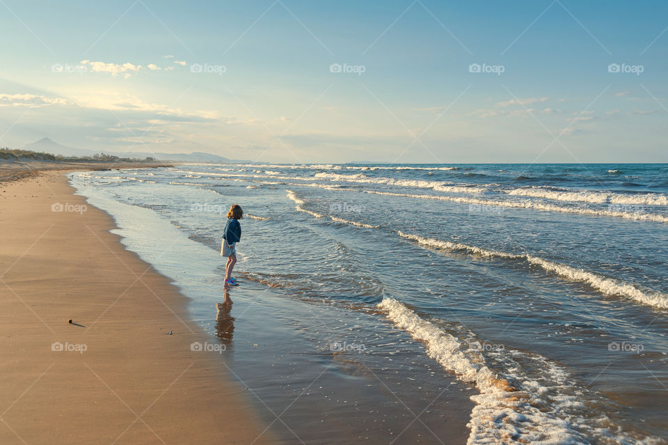 Young girl on a beach playing with waves.