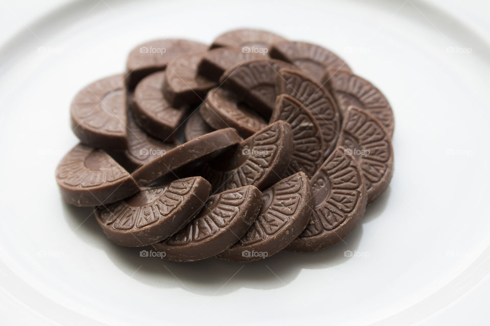 Chocolate shaped as orange slices on white plate 
