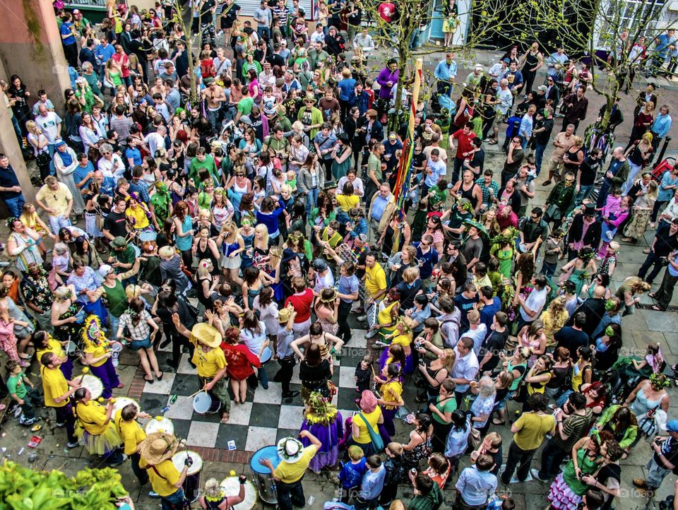 A lively crowd of people viewed from above dancing and celebrating as a yellow clad, samba band play.