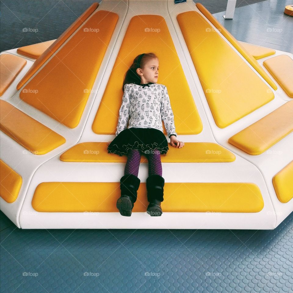 Little girl sitting on ride in amusement park