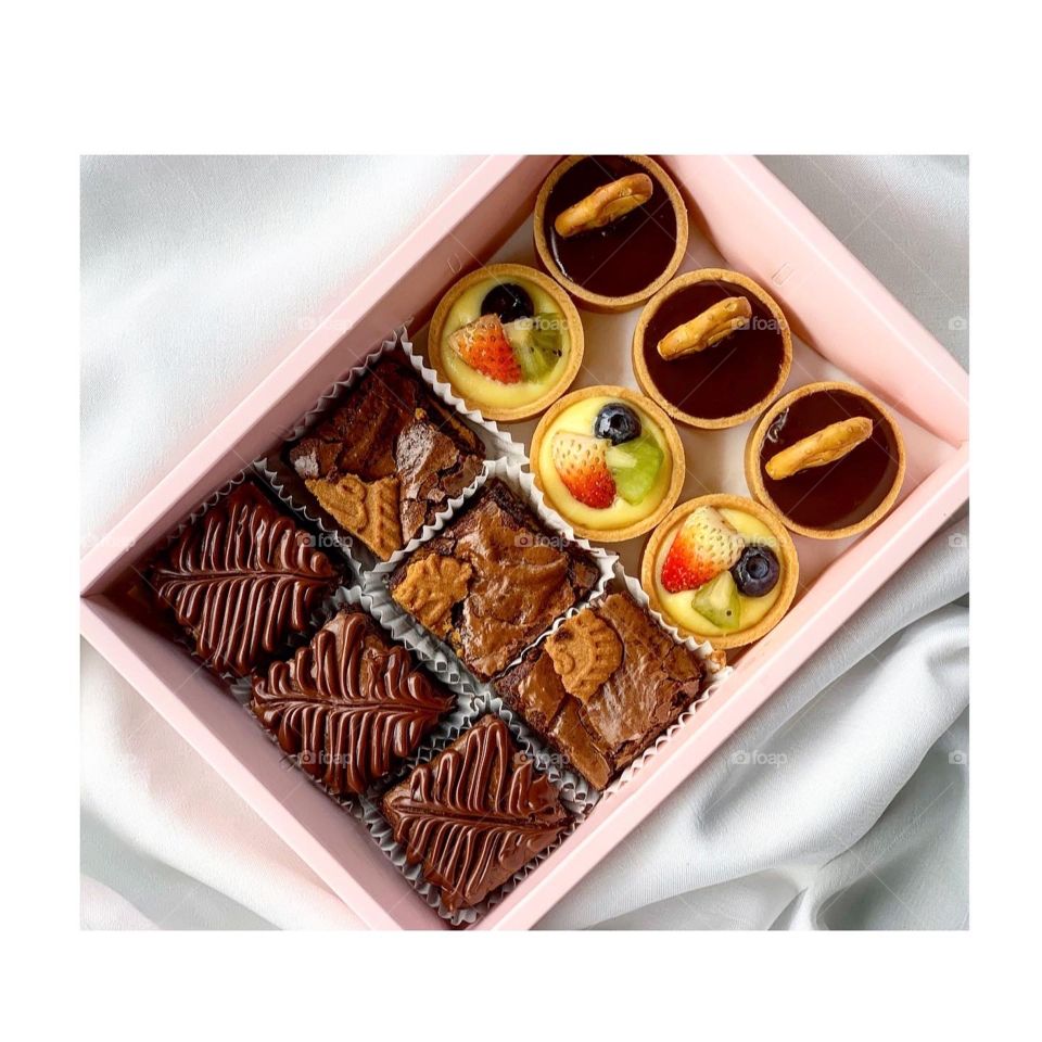 Bake box of brownies and fruit tarts nicely packed in a pink box 