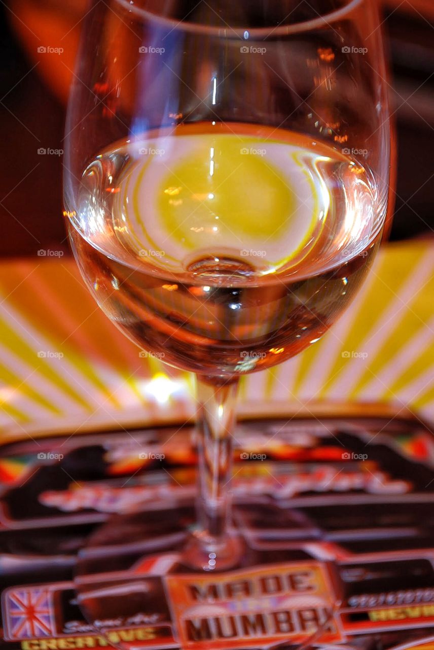 Quench. A glass of white wine set on bright yellow mat