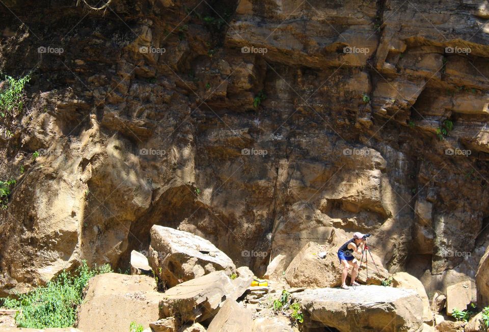 A young man with a camera and accompanying  equipment takes a photo of the surrounding landscape