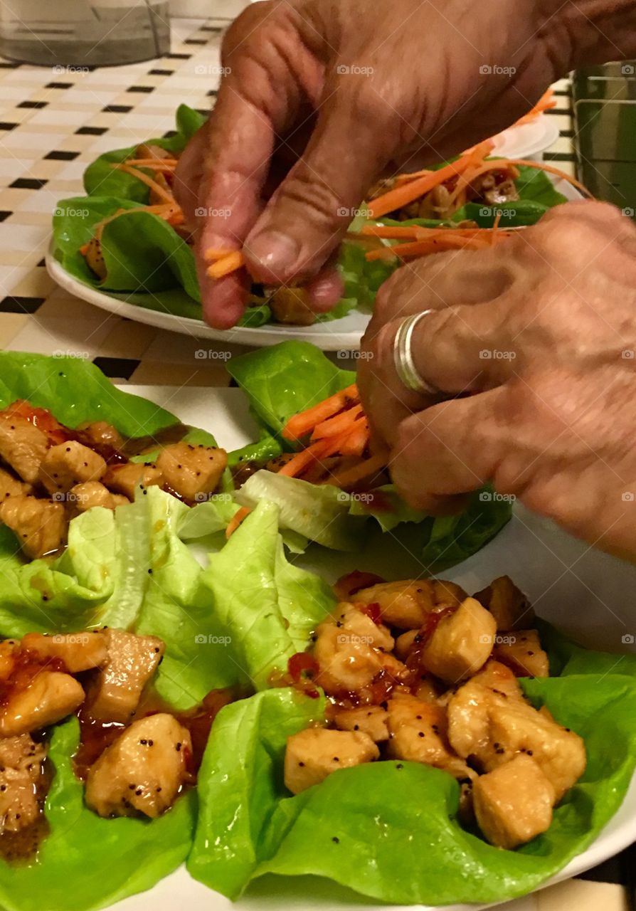 Human hands preparing Asian lettuce wraps.