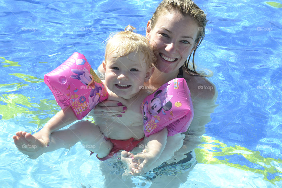 Mother playing and swimming in the pool with her two year old doughter on their family holiday in Turkey.