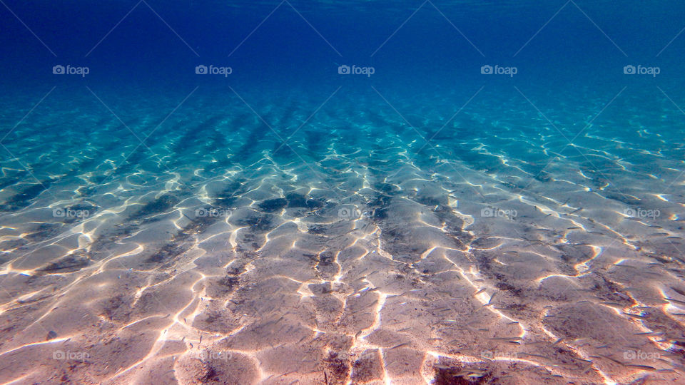 View of sand in deep blue sea underwater