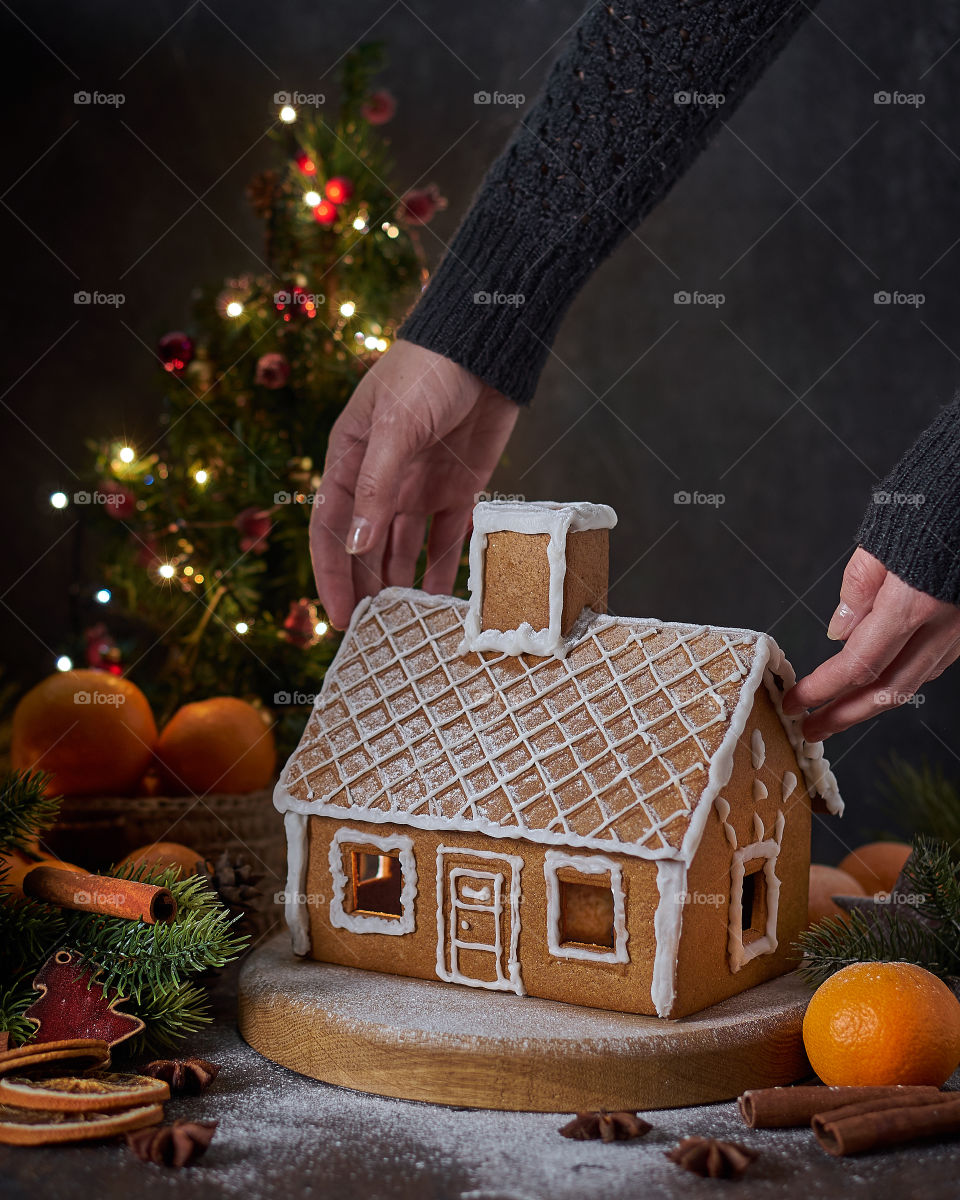 Female hands holding gingerbread house.