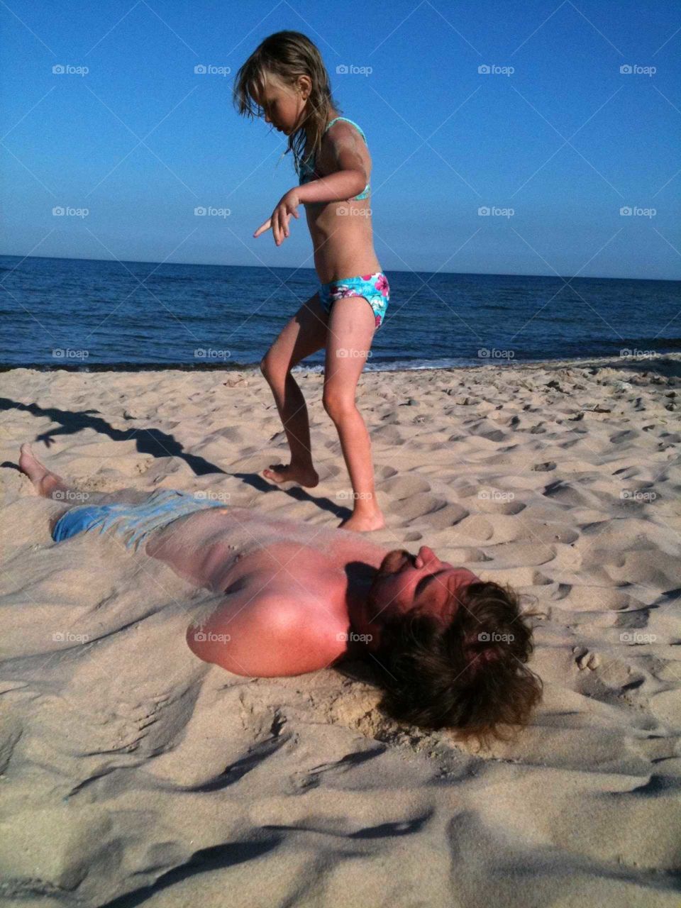 Daughter buries father in sand on the beach