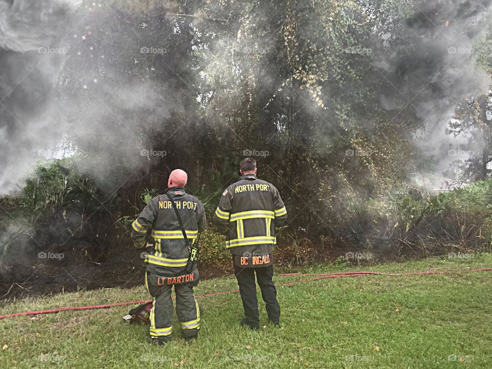 Firefighters in the smoke. Brave firemen surveying the scene.