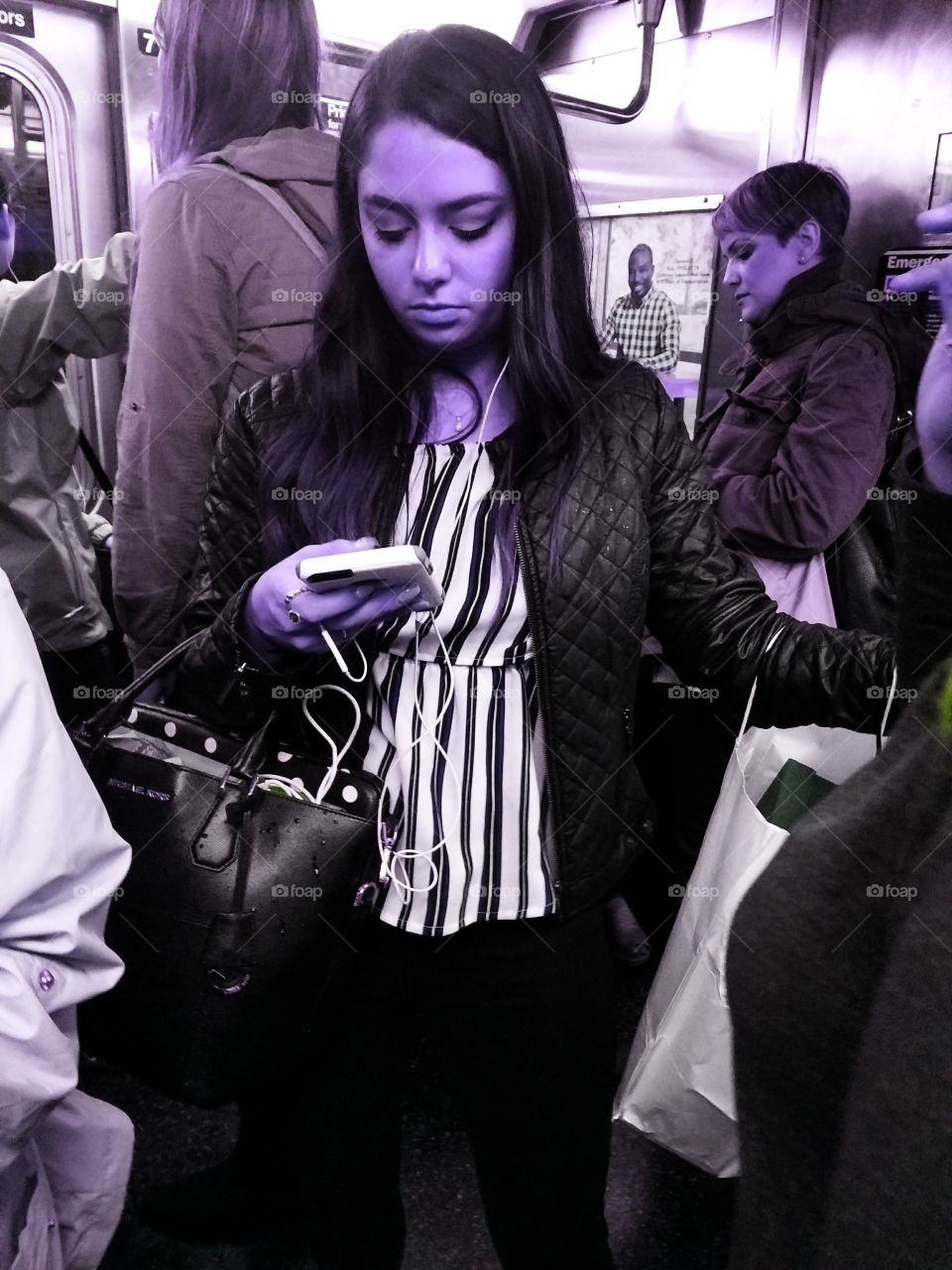 Girl Riding Subway in NYC Looking at her Phone. Purple Filter.