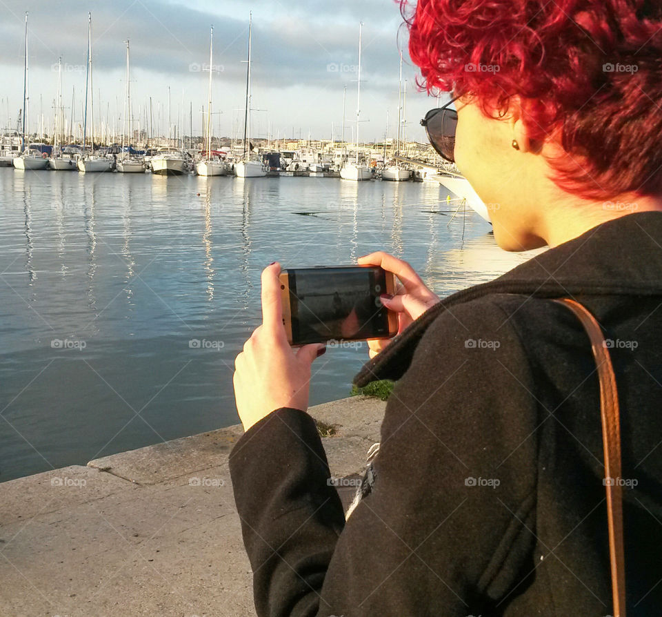 women photographer in Action with smartPhone in front of The sea