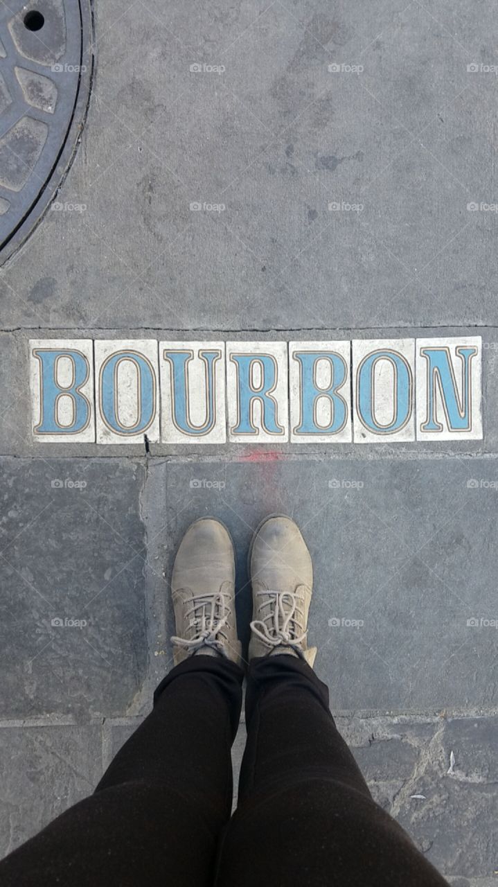 Feet in boots standing at Bourbon Street in New Orleans