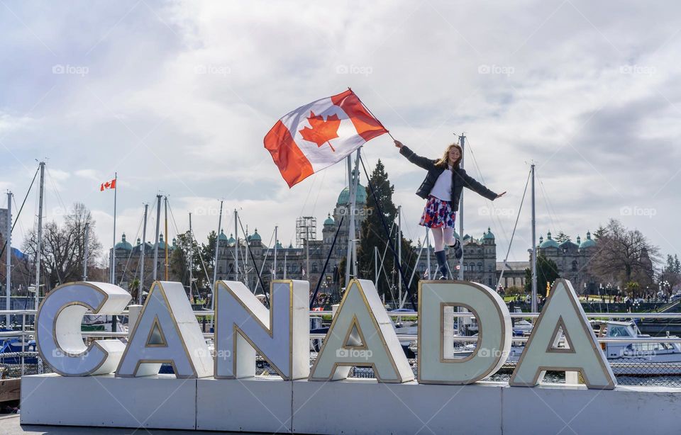 Girl balancing on Canada sign with Canada flag 