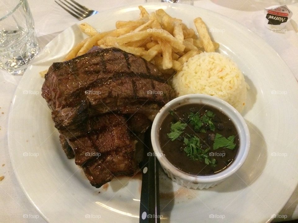 Steak dinner with frites and rice, together with a decadent au jus sauce on the side. 