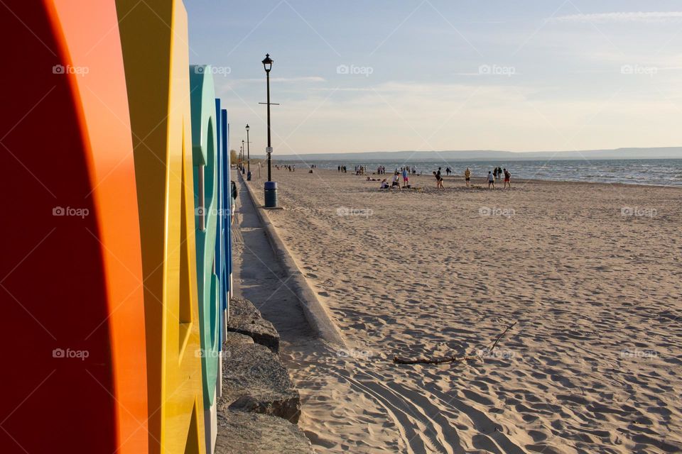 Sandy beach with people enjoying themselves with lampposts and colourful sign on the side