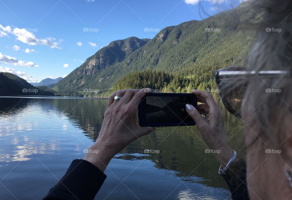 Woman taking photo at mountain lake