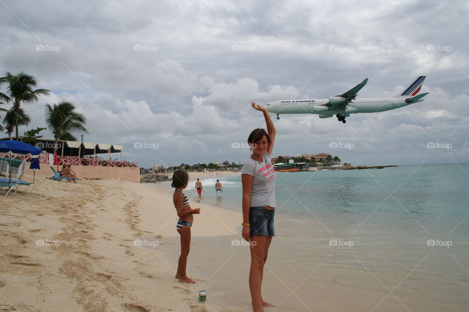 Woman standing in front flying airplane 