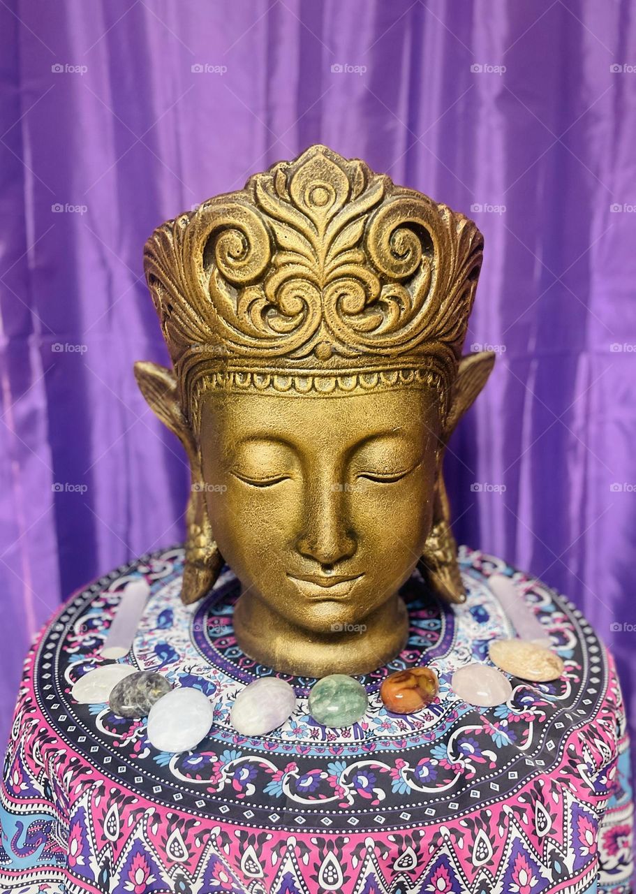 A Buddha meditating with several crystals in a peaceful environment.