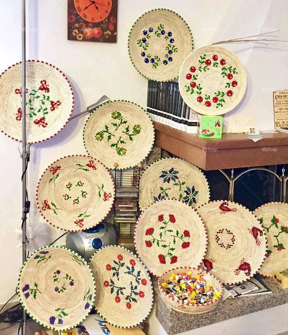 The image shows a group of hand -made dishes of wicker, decorated with colored embroideries with beautiful floral shapes, and is elegantly displayed in a warm corner that combines heritage and beauty, which gives the place an artistic spirit and attr