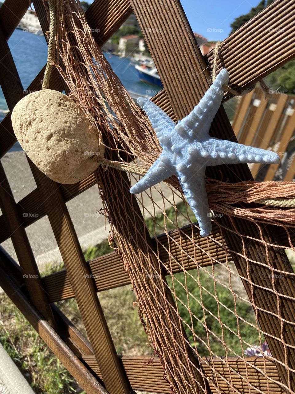 A sunny day, a fishing net, and a blue starfish by the sea.