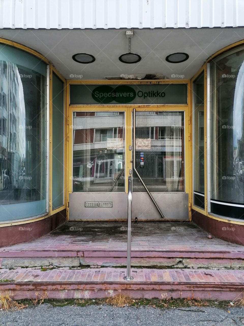 An old dilapidated building in the middle of a town that used to be a shop. No one walks through these doors anymore. Sad.