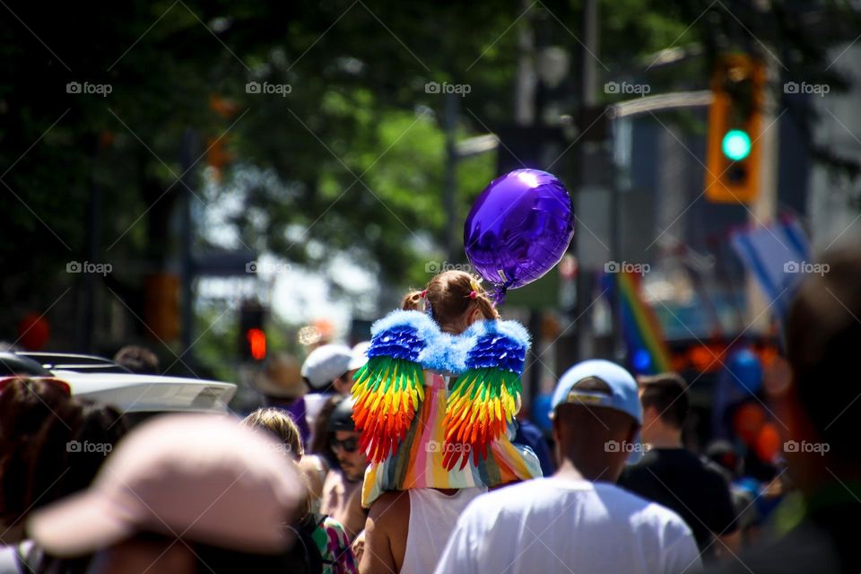 Girl with wings and purple balloon is carried by her father