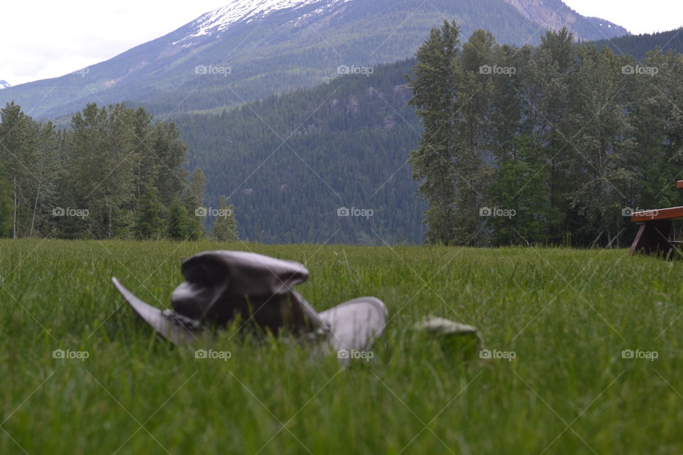 Australian leather bush hat on grass in alpine meadow agains a backdrop of Canada's snow capped Rocky Mountains 