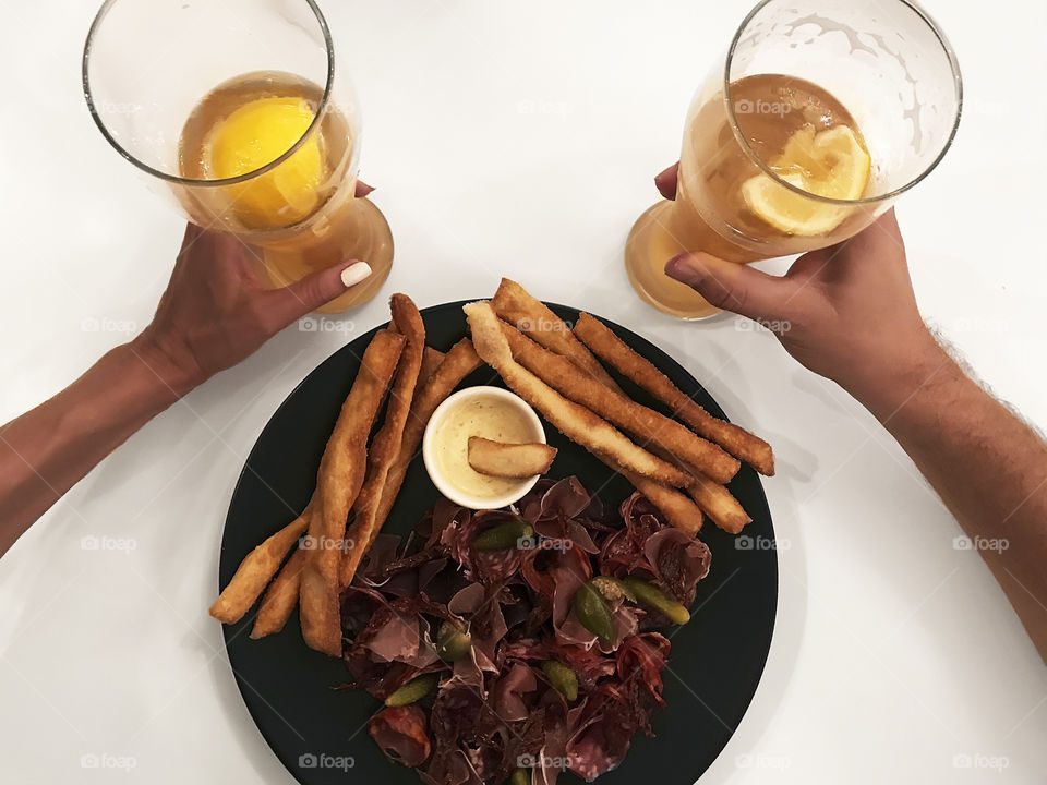 Overheard view of drinking two glasses of beer with a plate full of snacks 