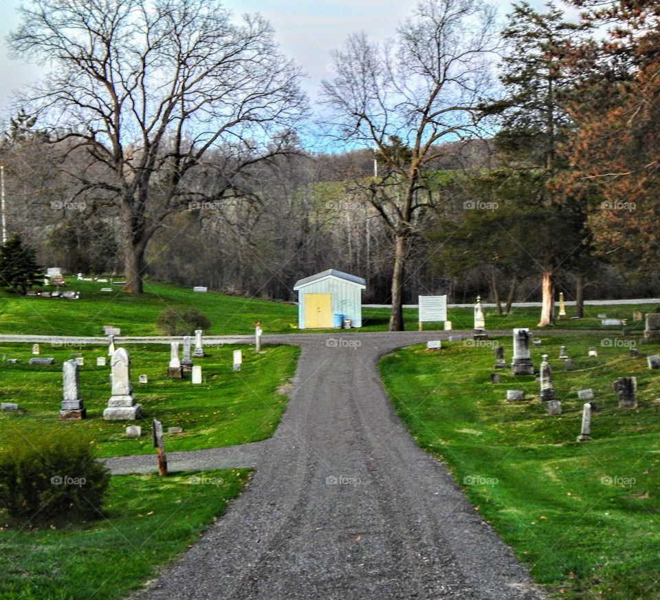 gravel pathway aligned with headstones leading to a cemetery building