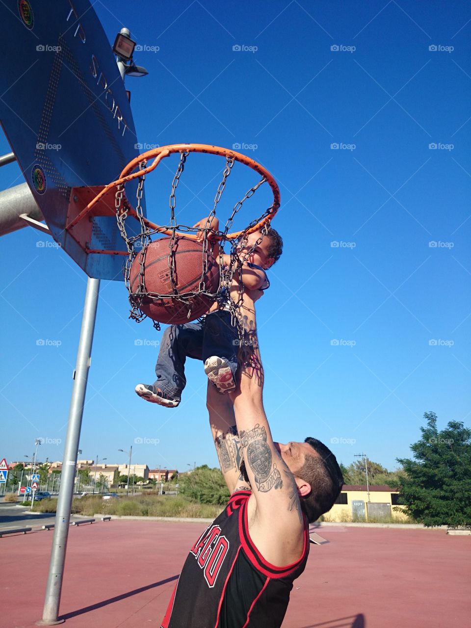 Man lifting his son for putting ball in basketball hoop