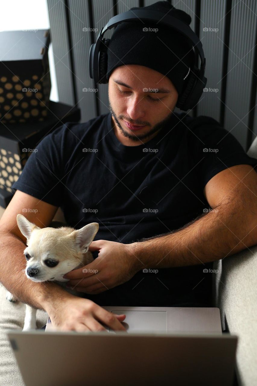 stylish guy in black clothes, with headphones and his best friend, a dog. a twenty-three-year-old teenager, a new generation.