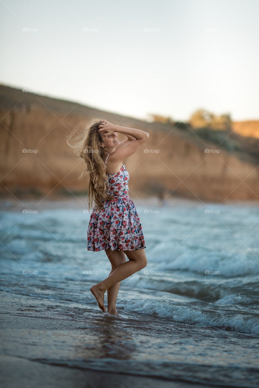 Portrait of beautiful young woman near the sea at sunset