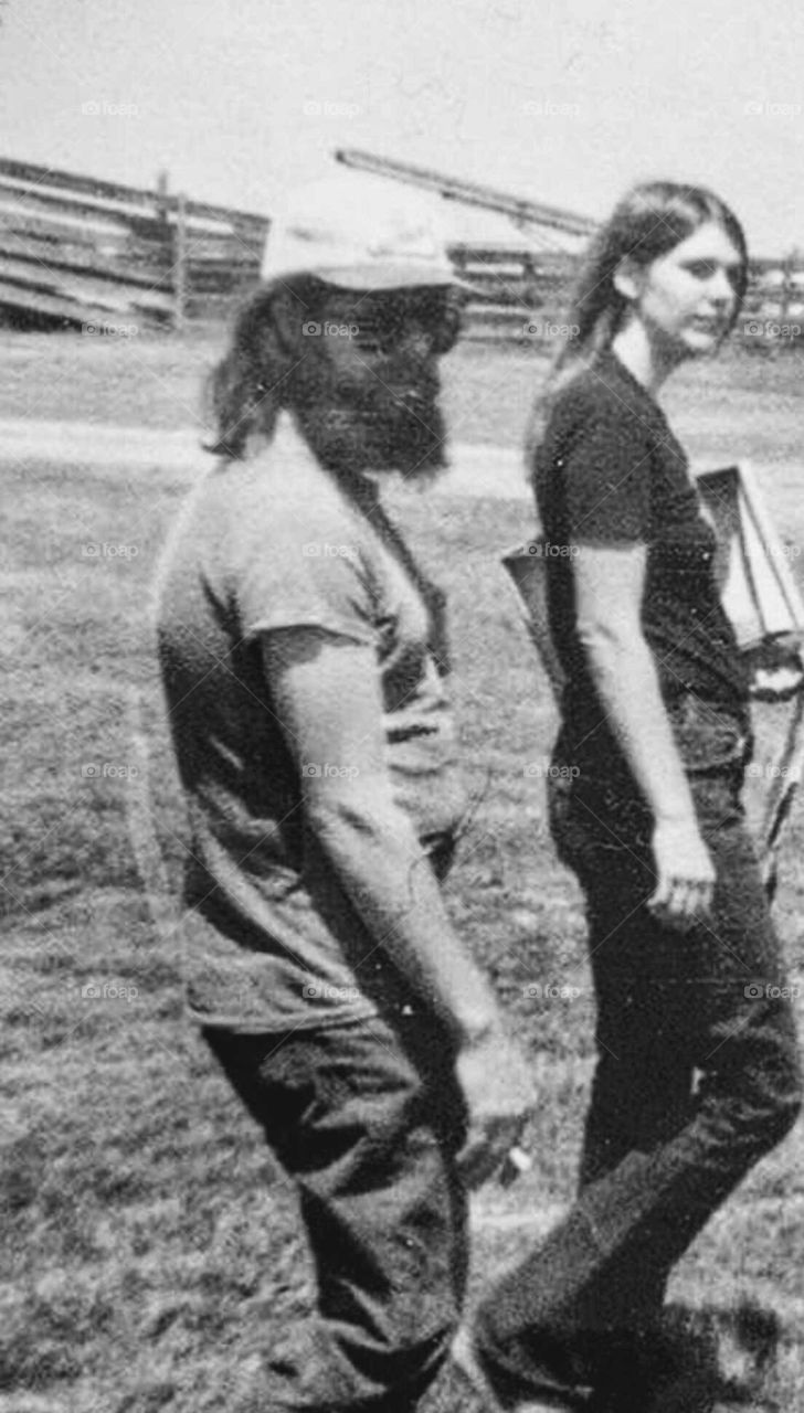 Bearded long haired American male Hippie smoking his cigarette as he is walking with his partner.