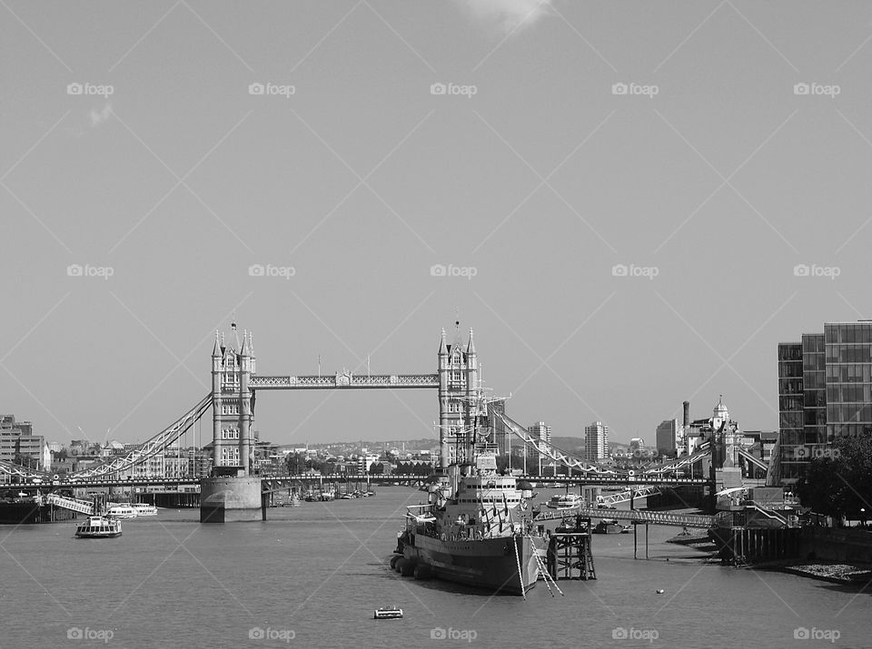 The HMS Belfast anchored on the Thames River in London with the Tower Bridge in the background on a sunny summer day. 
