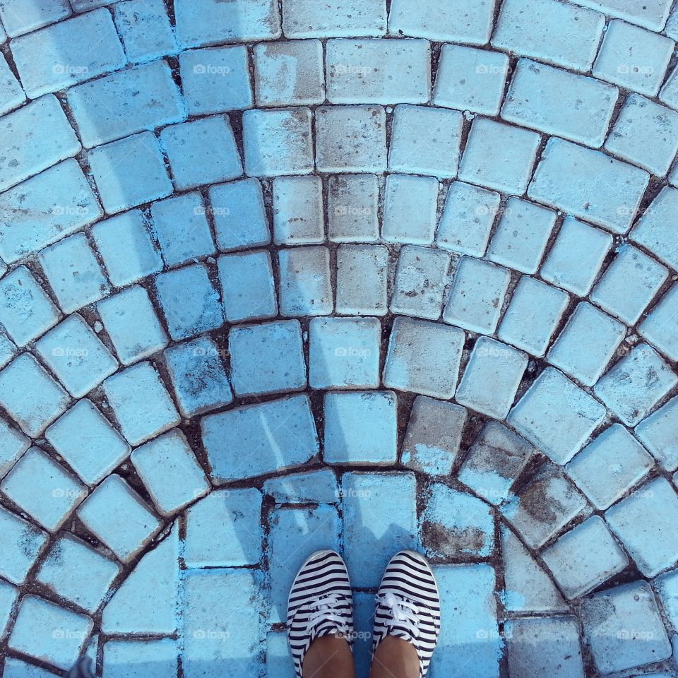 Footphoto. Topview on the foot staying on the blue colored bricks