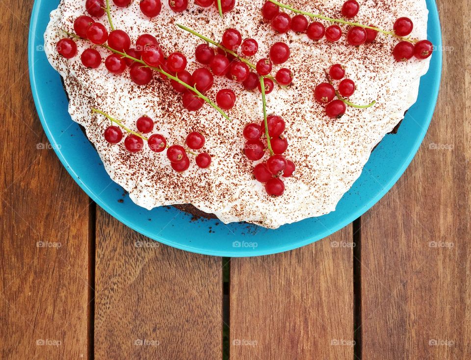Brownie cake covered with whipped cream and red curratns