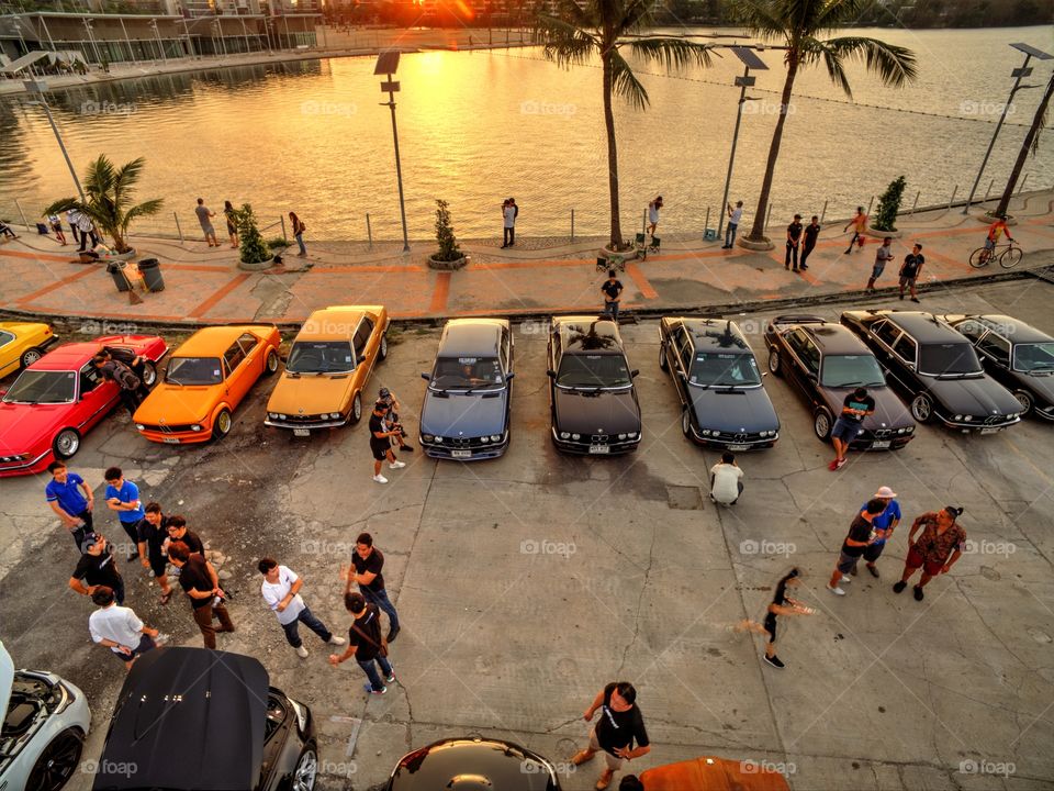 drone aerial view from above of bmw cars parked next to a lake