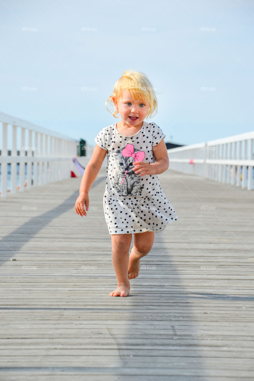 Little girl walking on boardwalk