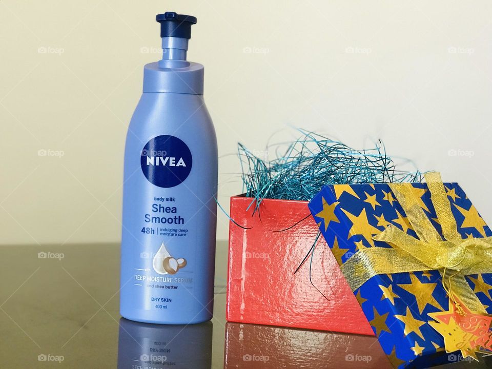 Nivea shea smooth lotion and blue and red gift box is filled with blue glitter strips.